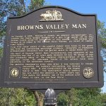 Historic Marker, Browns Valley Man, Minnesota, United States. TEXT: On October 9, 1933, William H. Jensen, an amateur archaeologist, uncovered the badly broken skeleton of a man in a gravel pit on the plateau visible about ½ mile south of this marker. The plateau was formed as an island in the ancient River Warren, an outlet of Glacial Lake Agassiz. From flint spear points of the parallel-flaked type found in the grave and from the surrounding geological evidence, University of Minnesota archaeologists estimated that the burial dated to about 6000 B.C. The skull of Browns Valley Man, reconstructed and measured at the university was that of an adult male between 25 and 40 years of age who possessed many of the physical characteristics of the North American Indian. No additional traces of his culture have been discovered in the immediate vicinity. The skeleton disappeared some time after it was returned to Jensen, deepening the mystery surrounding the Browns Valley Man. It was rediscovered by the Jensen family in 1987. The radiocarbon dating method has now dated the skeleton to 9,000 years ago. This makes the skeleton one of the earliest ever found, to date, in the New World.