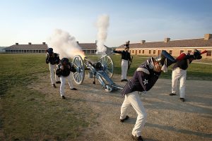 Five re-enactors dressed as U.S. soldiers in the 1820s fire a cannon on the parade grounds at Fort Snelling.