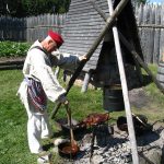 Re-enactor portraying a voyageur preparing food by a fire