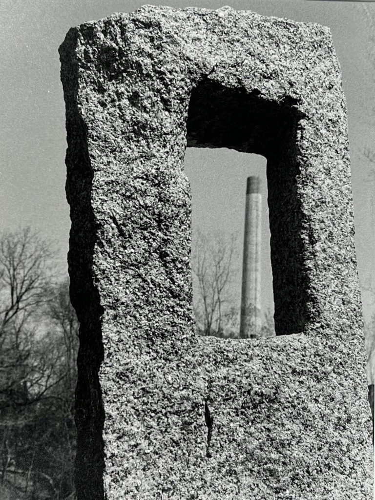 The central monument of "Swede Hallow Henge" with the Hams Brewery smokestack in the background. 2022