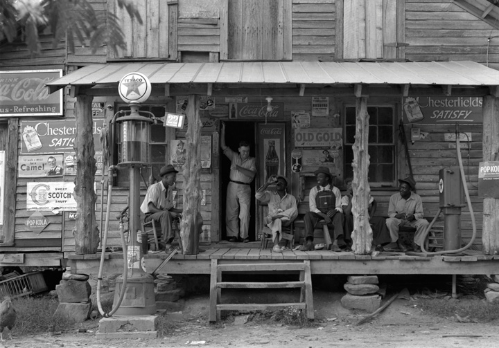 Men sitting out on the porch of an old wooden cabin