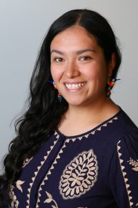 A portrait photo of Carolina Ortiz smiling, facing the camera wearing a dark blue shirt