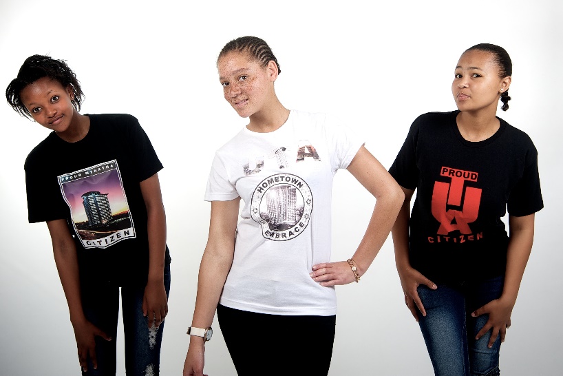 Three adolescent girls standing next to one another and looking into the camera.