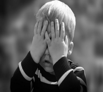 A young child covering his eyes with his hands.