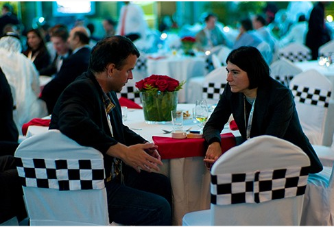 Two people sitting at a restaurant table having a conversation facing each other and making eye contact.