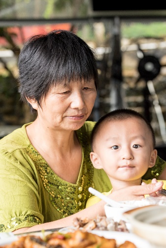 Grandmother with grandchild on her lap during a meal.