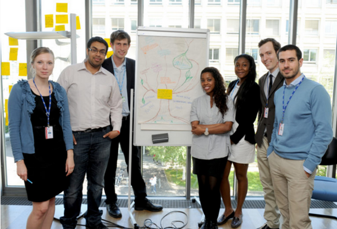 Young adults giving a presentation with a complex poster showing a diagram with many different ideas and directions.