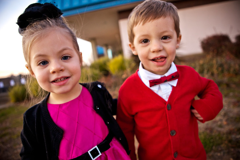Two fraternal twin toddlers, one boy and one girl, looking at a camera. They look very similar in age and size, and have different colored eyes.