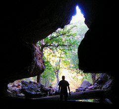 photo of man looking out from a cave