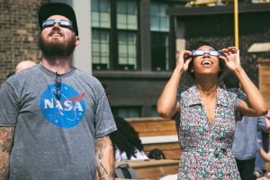 two people looking at the sky with protective glasses for an eclipse