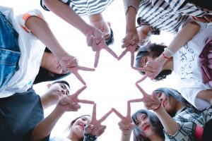 friends in a circle making a star with their finger and thumbs