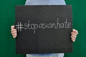 2 hands holding a sign that states, "#stopasianhate"