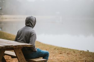 person sitting at a table looking at a foggy lake