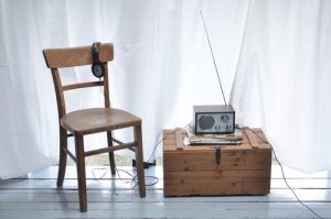 A chair, headphones, and a radio on a wood box.