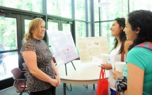 three women at a poster session for graduation