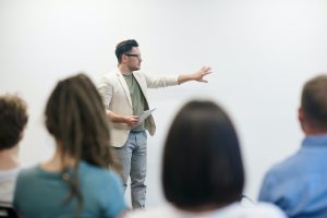 man speaking to a group at a white board