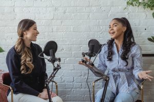 two women talking into microphones like a podcast