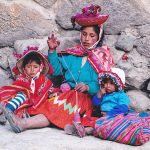 Quechua woman spinning with two children by her side